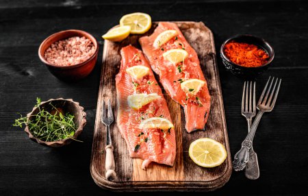 Photo for Fresh trout salmon filet with rosemary and lemons on wooden board ready served with spicies, pink salt and hearbs. Omega orange fish with citrus fruit for healthy nutrition - Royalty Free Image