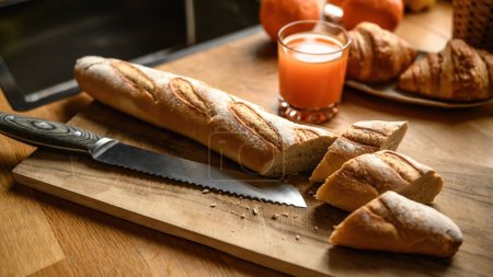 Foto de Baguette fresca en una tabla de cortar en la cocina. Cocinar desayuno francés fresco. - Imagen libre de derechos