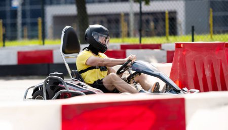 Hombre en casco protector conduciendo Go-Kart por pista de carreras Entettainment extremo