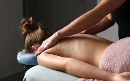 Foto de Profesional masajista masaje espalda y hombro hojas de joven mujer acostado en un masaje de mesa. - Imagen libre de derechos