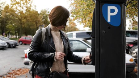 Téléchargez les photos : Femme paie pour le stationnement par l'intermédiaire du parcmètre et reçoit une contravention de stationnement - en image libre de droit