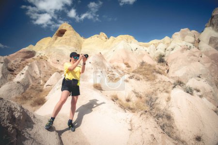 Foto de Mujer con cámara de pie en la colina de montaña en Capadocia, Turquía - Imagen libre de derechos