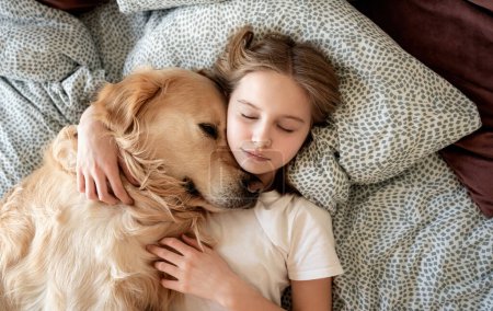 Foto de Linda niña abrazando perro y durmiendo en la cama - Imagen libre de derechos