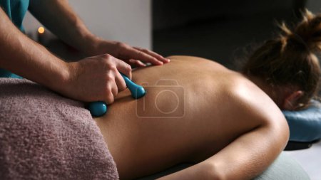 Foto de Masajista profesional haciendo masaje de espalda para niña con un masajeador en un salón de spa, columna vertebral saludable y procedimientos musculares de la espalda - Imagen libre de derechos