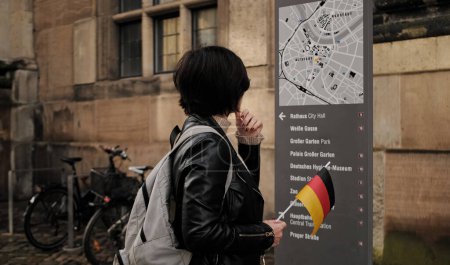 Foto de Atractivas caminatas turísticas femeninas con bandera de Alemania en el centro histórico de Dresde, chequeando la ruta turística en el mapa de la ciudad - Imagen libre de derechos