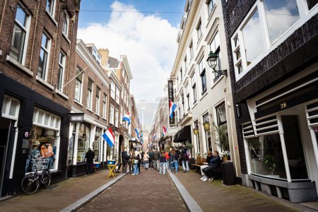 Téléchargez les photos : La Haye, Pays-Bas - 09 avril 2023 : Central Street avec des magasins de La Haye en Hollande. Rue avec des drapeaux nationaux sur un immeuble. - en image libre de droit