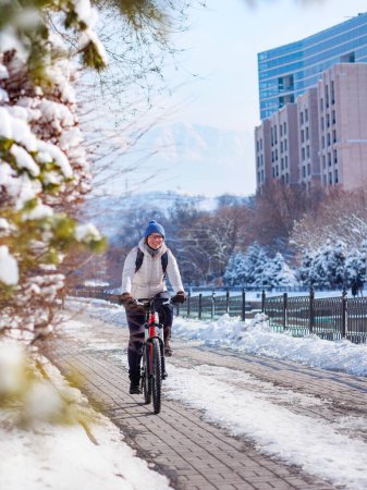 A sporty girl rides a bicycle around the city on a sunny winter day. Active lifestyle in winter. Ecological transport
