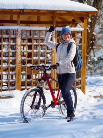 A girl with a bicycle in winter enjoys a nice sunny winter day. Active lifestyle in winter. Ecological transport