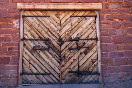 Zwei große Holztüren mit einer kleineren Tür bilden den Eingang zum Winsor Castle Fort am Pipe Springs National Monument in Arizona.