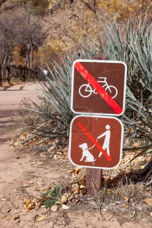 Signos que no muestran bicicletas ni mascotas en el sendero que conduce por el río Virgen hasta los Estrechos en el Parque Nacional Zion, Utah.