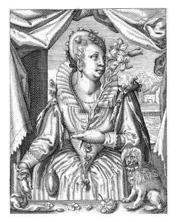 An elegant lady, standing behind a table, holds a flower branch in her hand and smells it. There is a dog on the table.