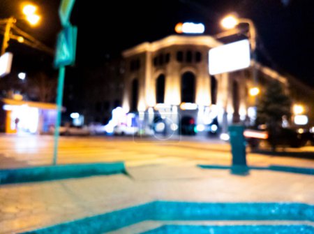Foto de Fondo borroso. Ciudad nocturna. Silueta borrosa de edificios, manchas bokeh de linternas brillantes. Vista borrosa de la calle de la ciudad.Efecto Bokeh. Calle nocturna desenfocada con desenfoque bokeh de luces de calle - Imagen libre de derechos