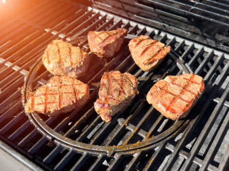 Beef fillet steak on the gas grill. Grilling of beef meat on outdoor gas grill. Grilled meat steak on stainless grill depot