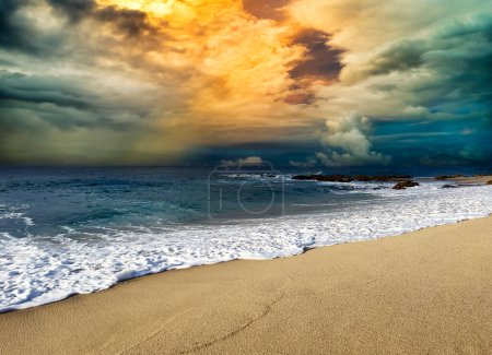 Foto de Nublado atardecer dorado en el Océano Pacífico con playa de arena en frente - Imagen libre de derechos