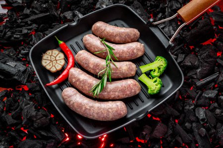 Téléchargez les photos : Raw stuffed sausages on srill pan. Hot coals of gil - en image libre de droit