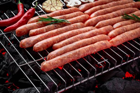 Téléchargez les photos : Raw sausages on a hot charcoal grill. Home picnic photo - en image libre de droit