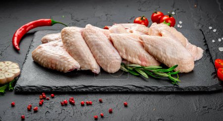 Téléchargez les photos : Raw chicken wings on a black kitchen table. Healthy food concept. - en image libre de droit