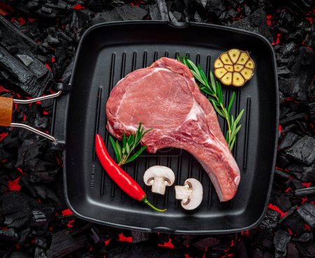 Téléchargez les photos : Raw beef steak on the grill pan, on burning charcoal barbeque - en image libre de droit