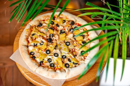 Téléchargez les photos : Délicieuse pizza avec viande de poulet, ananas, maïs et olives. Vue du dessus de la grande pizza - en image libre de droit