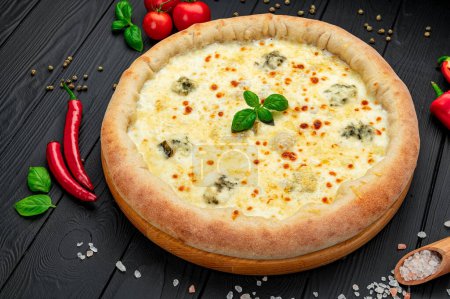 Téléchargez les photos : Hot quatre fromages délicieuse pizza américaine rustique maison avec croûte épaisse sur table noire. Vue du dessus de la grande pizza - en image libre de droit