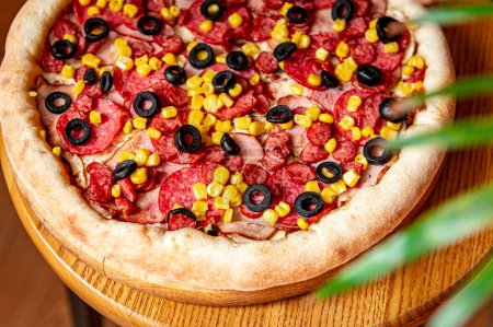 Téléchargez les photos : Pizza savoureuse et grande avec différents types de viande. Pizza aux saucisses, jambon, maïs et olives. Vue de dessus de pizza chaude. - en image libre de droit
