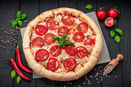 Téléchargez les photos : Pizza Margherita sur fond noir, vue de dessus. Pizza Margarita aux tomates, basilic et fromage mozzarella close up. - en image libre de droit