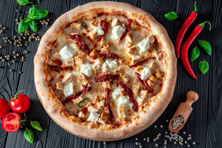 Téléchargez les photos : Pizza savoureuse et grande avec différents types de viande. Vue de dessus de la pizza chaude. Grande et savoureuse pizza aux tomates séchées au soleil et au fromage feta - en image libre de droit