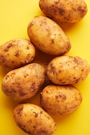 Téléchargez les photos : Patates crues sur fond jaune. Contexte alimentaire abstrait - en image libre de droit