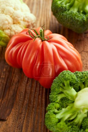 Foto de Food still life with tomato, broccoli and cauliflower on wooden table - Imagen libre de derechos