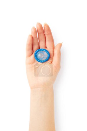 Téléchargez les photos : Main de femme tenant un préservatif bleu dans la paume isolé sur fond blanc - en image libre de droit