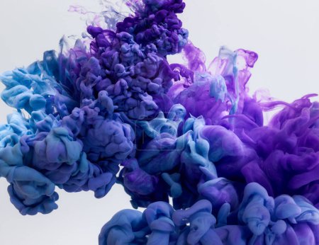 Foto de Salpicadura de pinturas azules y púrpuras en agua sobre fondo gris - Imagen libre de derechos