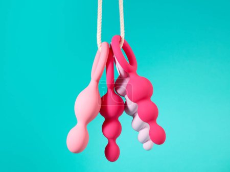Téléchargez les photos : Ensemble de jouets sexuels roses accrochés à une corde sur fond de cyan bleu - en image libre de droit
