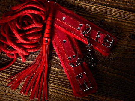 Téléchargez les photos : BDSM jouets sexuels dans une couleur rouge sur des planches de bois vieilli toile de fond - en image libre de droit