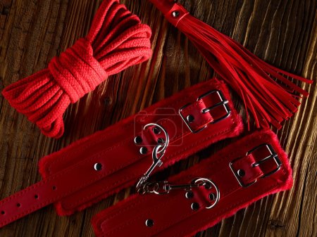 BDSM sex toys set in a red color over aged wooden planks backdrop