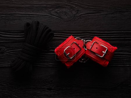 Téléchargez les photos : Fond BDSM avec menottes pelucheuses rouge vif et corde pour attacher - en image libre de droit