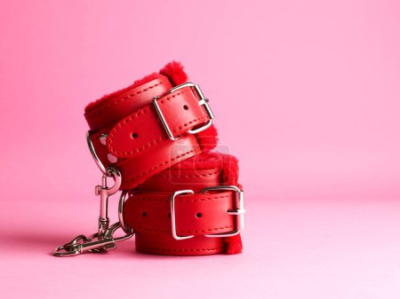 Foto de Pareja roja de esposas para juegos sexuales sobre fondo rosa - Imagen libre de derechos