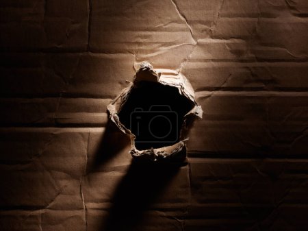Photo for Abstract grunge crumpled cardboard surface texture with hole in the middle lighted by sunbeam - Royalty Free Image