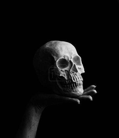 Foto de Manos ensangrentadas de una bruja sosteniendo cráneo humano sobre fondo negro - Imagen libre de derechos