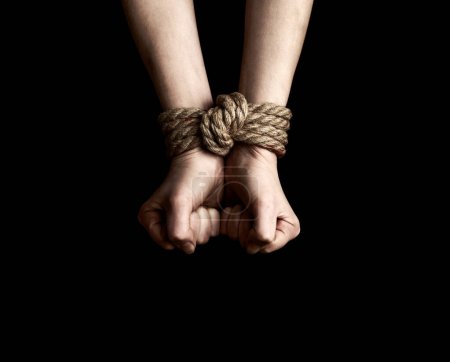 Photo for Hostage hands tied with a rope over black background - Royalty Free Image