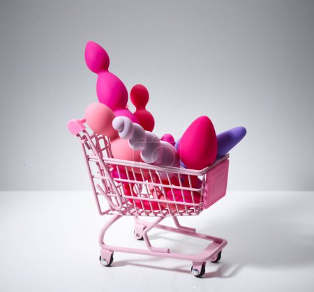 Téléchargez les photos : Anal plugs and dildo sex toys in shopping basket isolated on white background - en image libre de droit
