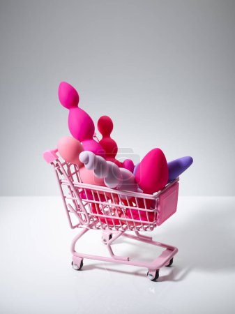 Téléchargez les photos : Anal plugs and dildo sex toys in shopping basket isolated on white background - en image libre de droit