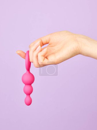 Foto de La mano de la mujer sosteniendo juguetes sexuales para adultos sobre fondo violeta - Imagen libre de derechos