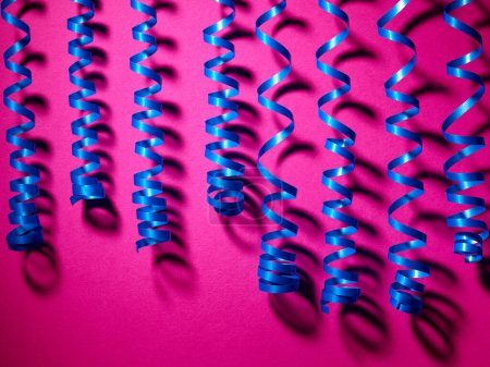 Foto de Cintas decorativas de serpentina azul sobre fondo rosa - Imagen libre de derechos
