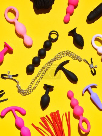 Téléchargez les photos : Bright sex toys background. anal plugs and dildo over yellow paper backdrop - en image libre de droit