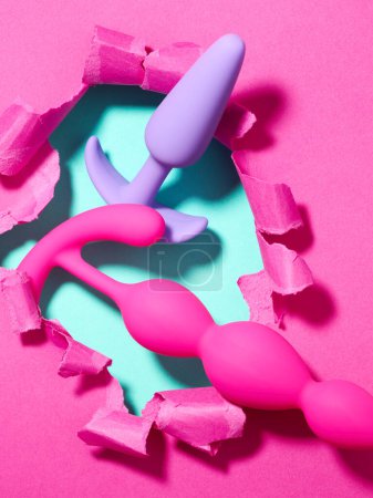 Sexspielzeug über Loch in rosa Papier Hintergrund