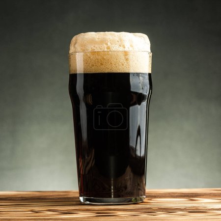 Téléchargez les photos : Un verre de bière brune artisanale froide sur fond sombre. Modèle de maquette - en image libre de droit