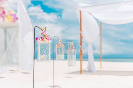 Téléchargez les photos : Auvent élégant avec des décorations en tissu blanc sinueux et des lanternes sur la plage - en image libre de droit