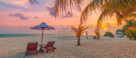 Tranquil romantic beach scene. Couple chairs umbrella, exotic tropical beach landscape for background wallpaper. Panoramic summer vacation holiday banner. Resort shore, palm leaves sunset sea sky sand