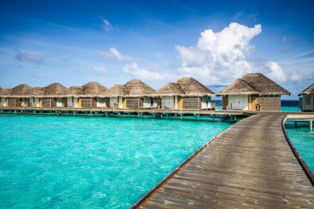 Téléchargez les photos : Resort de luxe avec villas aquatiques turquoise océan lagune paysage marin. Voie jetée en bois, ciel idyllique. Bungalows destination paradis. Vacances d'été et vacances, station balnéaire sur île tropicale - en image libre de droit