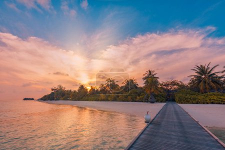 Foto de Puesta de sol en la isla de Maldivas, lujoso complejo de madera camino del muelle. Fantástico cielo colorido nubes reflejo playa mar horizonte. Vacaciones románticas de verano, concepto de viaje. Paraíso puesta de sol paisaje - Imagen libre de derechos